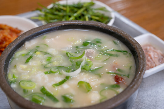 Traditional Korean dwaejigukbap pork soup served hot in a clay pot with side dishes.