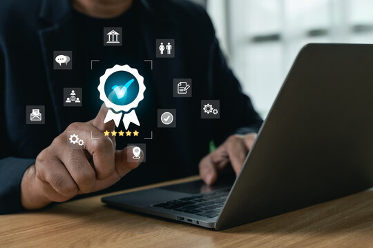 Businessman touching a glowing certified stamp icon with five stars while working on a laptop, concept of quality assurance, customer satisfaction, and standard guarantee.