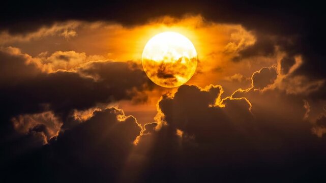 Low angle timelapse sun on blue sky concept. Dramatic sunset with glowing sun behind dark clouds and golden sky rays in vibrant nature scene