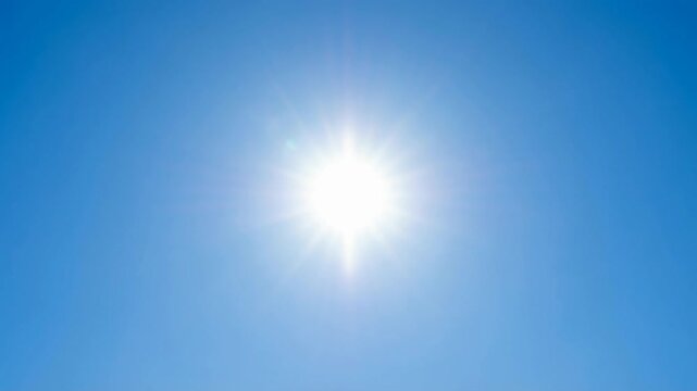 Low angle timelapse sun on blue sky concept. Bright sun shining in clear blue sky on a sunny day with radiant sunlight and blue background