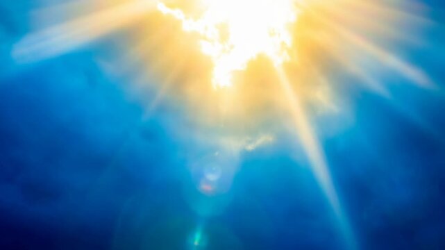 Bright sun shining through soft clouds with radiant light beams in a clear blue sky