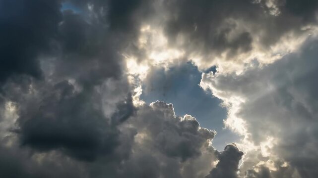 Dramatic cloudy sky with sun rays breaking through dark storm clouds creating a bright natural light