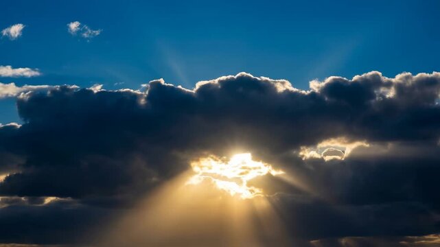 Sun rays breaking through dramatic dark clouds with a bright sky and golden light beams