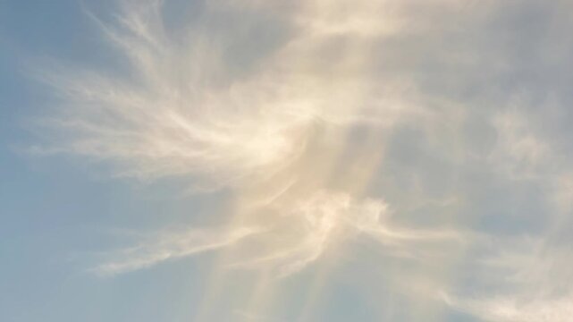 Soft sunlight filtering through delicate wispy clouds in a calm blue sky