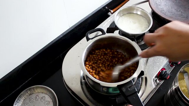 Vertical close-up of mixing cooked toor dal into a spiced curry in a home kitchen. Ideal for Indian recipe tutorials, cooking shows, food blogs, and traditional cuisine content.