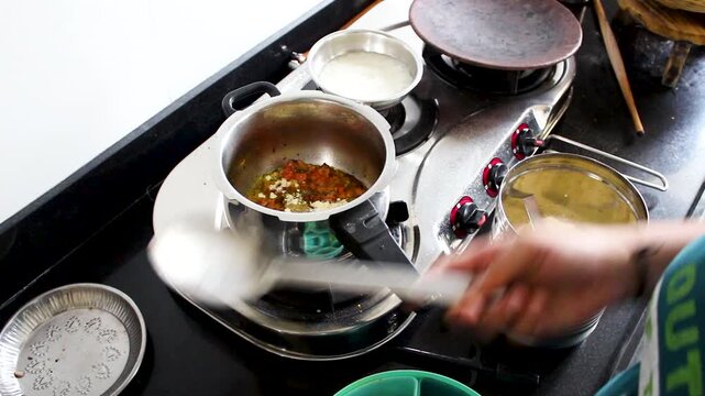 Vertical close-up of adding gram flour to simmering Indian curry in home kitchen. Ideal for recipe tutorials, food blogs, cooking shows, and traditional cuisine content.