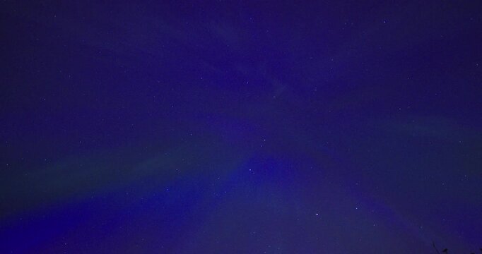 Faint purple and green aurora borealis stretching across a clear starry night sky. Minimal celestial background with subtle northern lights and abundant copy space for atmospheric nature or astronomy