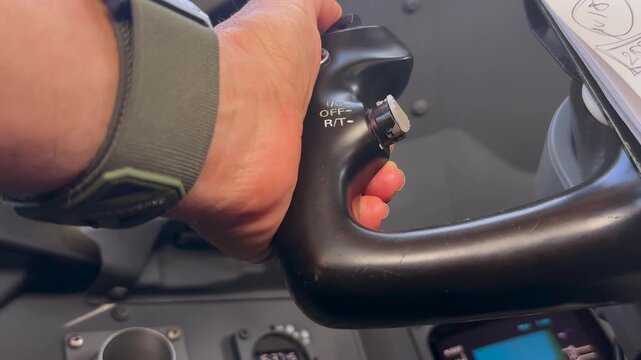 Extreme closeup view of the hand of a caucasian pilot pushing the autopilot disconnect button to take manual control inside a modern jet cockpit.