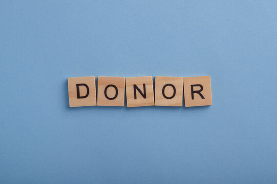 Wooden letter blocks spelling donor on a blue background, representing charitable giving, philanthropy, fundraising, financial support, nonprofit organizations, and humanitarian aid.