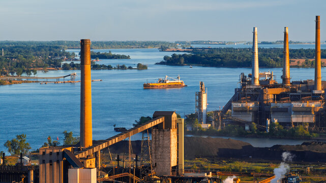 Industrial power plant operating by river with boat