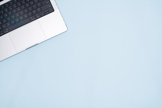 Top View of Laptop Keyboard on Pastel Blue Background with Copy Space