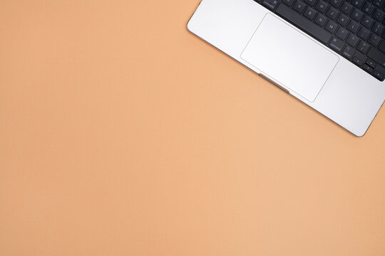 Top View of Laptop on Peach Background with Large Copy Space