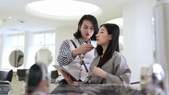 Hairdresser stylist talking consults with female customer for service before hair appointment, hairstylist man giving haircut grooming or comb hairstyle to client at beauty salon barber shop business