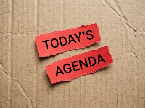 Two torn red paper pieces with "TODAY'S AGENDA" text on a rough cardboard background, planning Concept