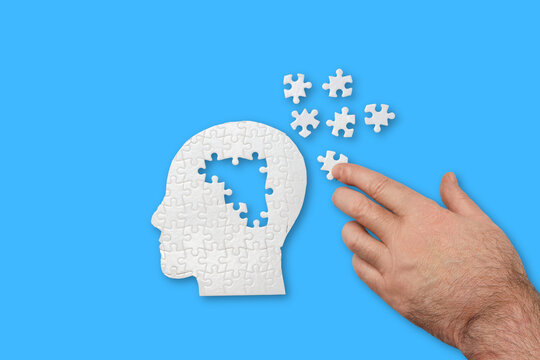 Hand assembles puzzle into head silhouette on blue