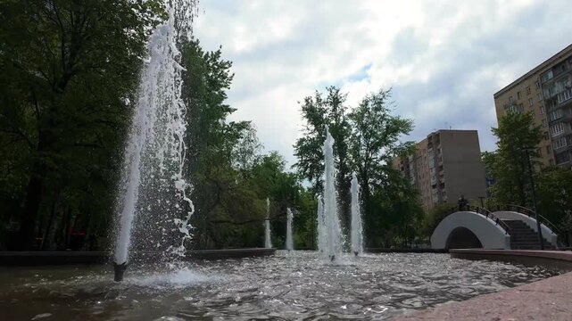 Moscow, Russia. The Stolby fountain on Ukrainian Boulevard, powerful vertical water jets rising from a broad basin, low-angle view on a cloudy spring morning