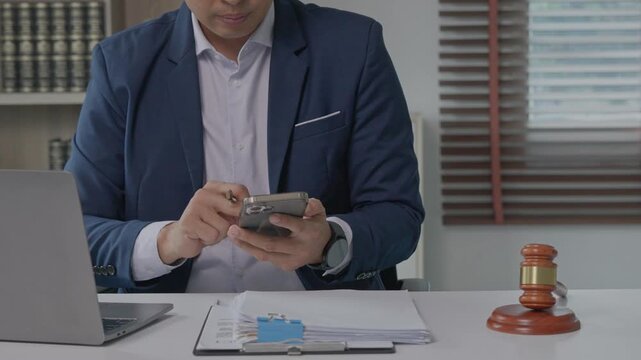 Male lawyer using smartphone at his desk in legal office