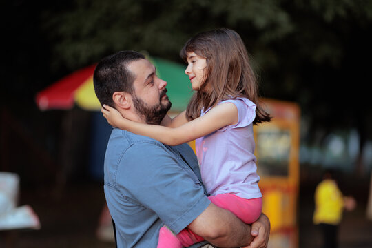 Loving Father Holding His Little Daughter Tightly In His Arms. happy dad hugs a cheerful toddler girl during family leisure time
