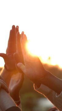 Group of Diverse People Raising Hands Together in Unity at Sunset, Celebrating Success and Teamwork