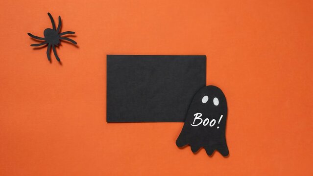 Halloween decorations flat lay ghost spider and blank card on orange background