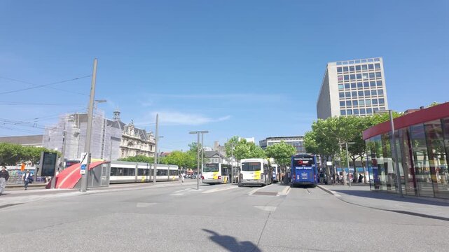 Urban transport hub in Antwerp, Belgium with buses and a tram on a sunny summer day.