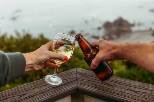 Couple toasting wine and beer by the ocean