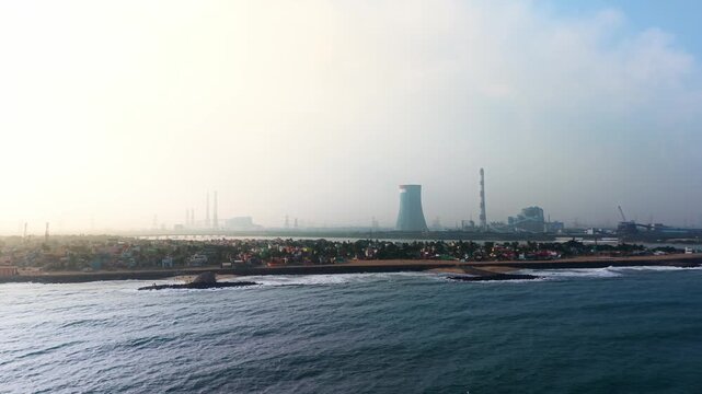 Coal fired thermal power plant with cooling towers on the sea shore emitting smoke