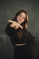 A cheerful teenage girl with long brown hair and glasses is smiling