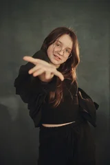 A cheerful teenage girl with long brown hair and glasses is smiling © Cavan