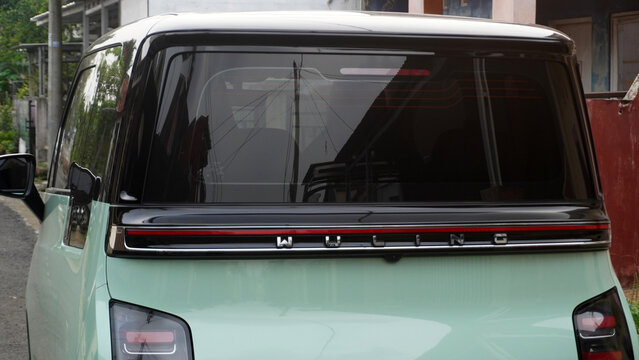 Purwokerto, Indonesia - 4 July 2026: Rear view of a mint green Wuling Air EV electric minivan with tinted windows parked on a residential street.
