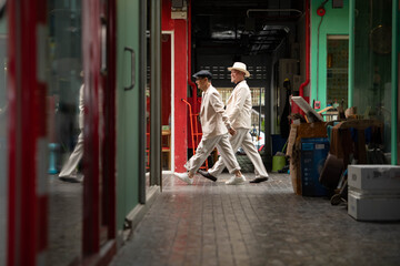 Naklejka premium Senior gay couple walking through a vibrant urban passageway, exploring local culture