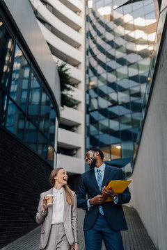 Happy business colleagues walking and laughing outdoors in city