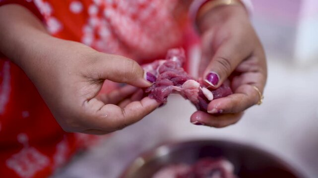 A married Indian woman hygienically cleans fresh red mutton pieces by hand in a clean kitchen, emphasizing food safety, cleanliness, traditional cooking, and careful meat preparation