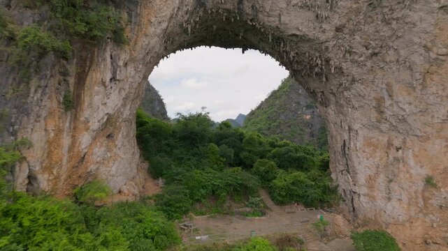 Drone pull-out video from inside Moon Cave, revealing the natural arch of Moon Hill and the unique karst mountain geological landscape of Guilin, China.