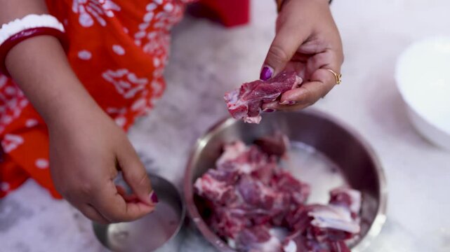 A married Indian woman hygienically cleans fresh red mutton pieces by hand in a clean kitchen, emphasizing food safety, cleanliness, traditional cooking, and careful meat preparation