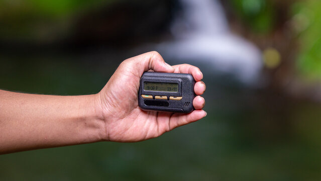 Hand holding pager beeper device, retro phone 90s instant communication and connection, sms messaging in the early 80s 90s digital age