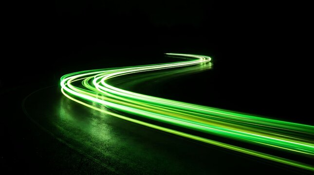 Green light trails on a winding road at night showcasing motion and speed in urban landscape