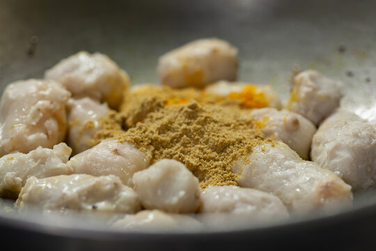 Indian woman adding turmeric to boiled taro root curry