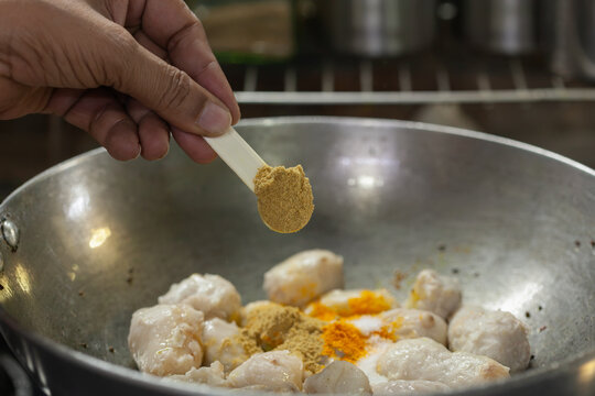 Indian woman adding turmeric to boiled taro root curry