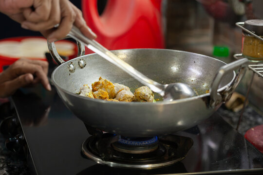 Indian woman adding turmeric to boiled taro root curry