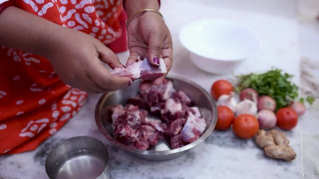 A married Indian woman hygienically cleans fresh red mutton pieces by hand in a clean kitchen, emphasizing food safety, cleanliness, traditional cooking, and careful meat preparation