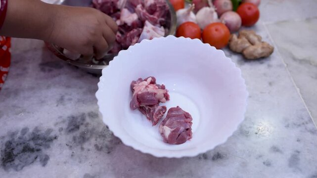 A married Indian woman hygienically cleans fresh red mutton pieces by hand in a clean kitchen, emphasizing food safety, cleanliness, traditional cooking, and careful meat preparation.