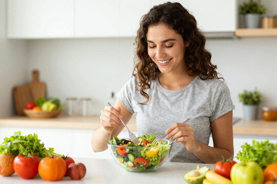 Woman preparing salad at kitchen counter in home