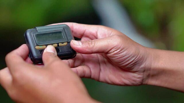 Hand holding pager beeper device, retro phone 90s instant communication and connection, sms messaging in the early 80s 90s digital age