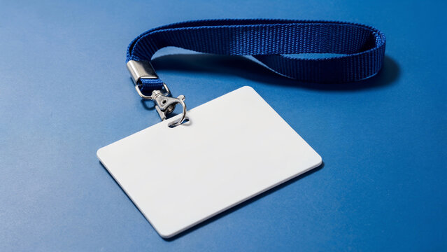 Blank white badge holder with blue lanyard on a blue textured surface, ideal for event access, corporate identification and security passes
