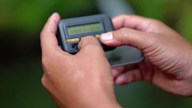 Hand holding pager beeper device, retro phone 90s instant communication and connection, sms messaging in the early 80s 90s digital age