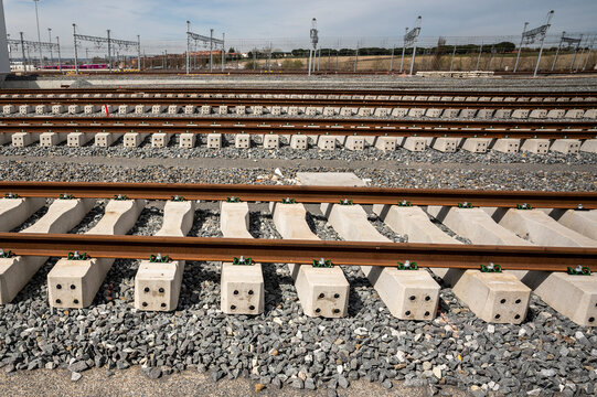Parallel railway tracks with concrete sleepers on gravel ballast at a depot.