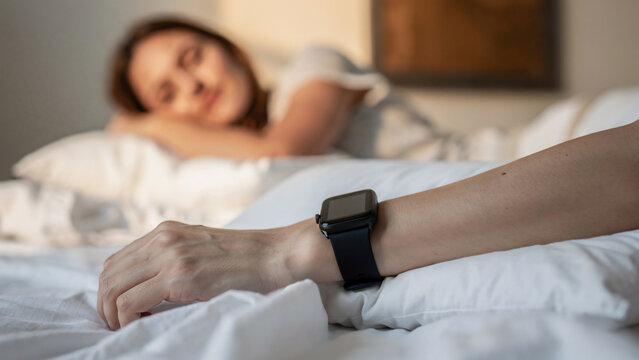 Close-up on a person's arm wearing a smartwatch while sleeping, suitable for health tracking, lifestyle promotion and sleep monitoring advertising