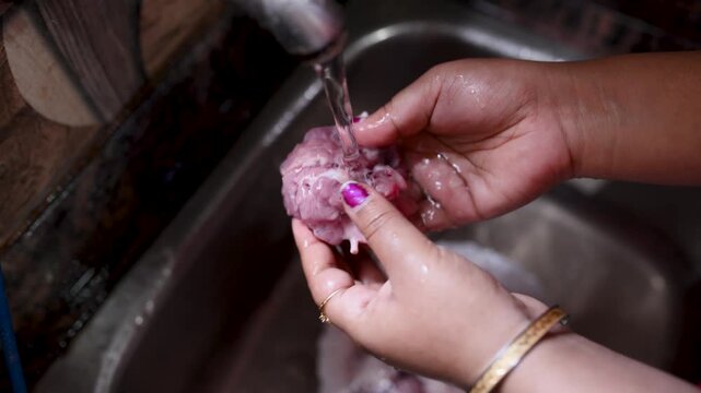 An Indian married woman hygienically washing fresh raw mutton in a kitchen basin before cooking. Close-up of clean red meat preparation, traditional home cooking, food safety, healthy meal preparation