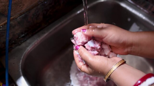 An Indian married woman hygienically washing fresh raw mutton in a kitchen basin before cooking. Close-up of clean red meat preparation, traditional home cooking, food safety, healthy meal preparation